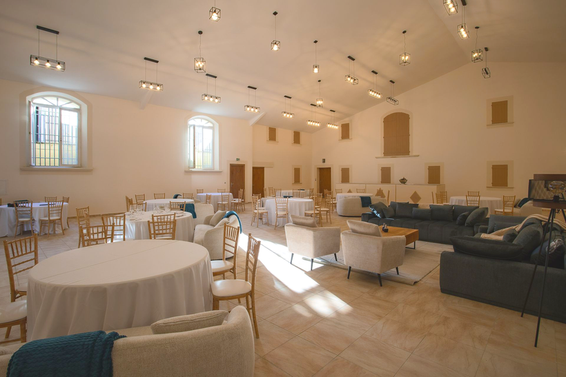 La salle de réception du Domaine de la Myrtille dressée pour un mariage — tables rondes sous la charpente